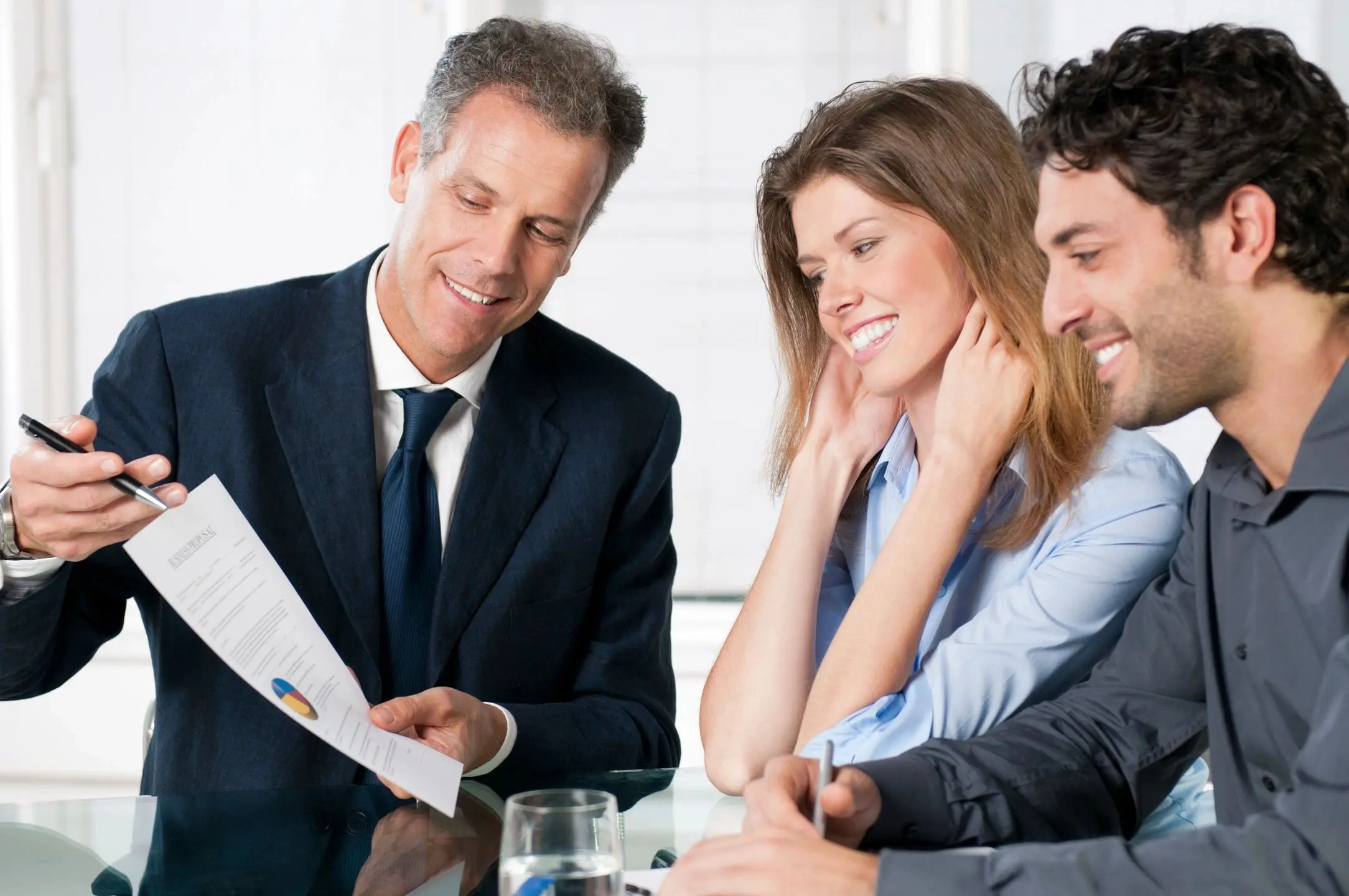 A professional discussing documents with a couple in a business setting.